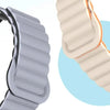 Close-up view of two adjustable magnetic loop watch bands, one gray and one orange.