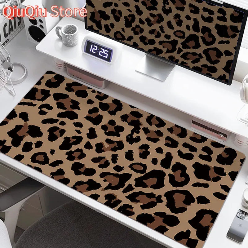 A large leopard print desk pad is displayed on a white desk next to a digital clock and other accessories.
