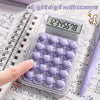 A clear plastic case holds a purple 8-digit wide-screen calculator with a keypad and a stylus on a sheet of mathematical pape