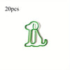 A single green paper clip shaped like a sitting dog, used as a cute desk organizer.