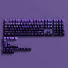 A close-up view of a purple PBT keycap set for mechanical keyboards displayed against a solid purple background.