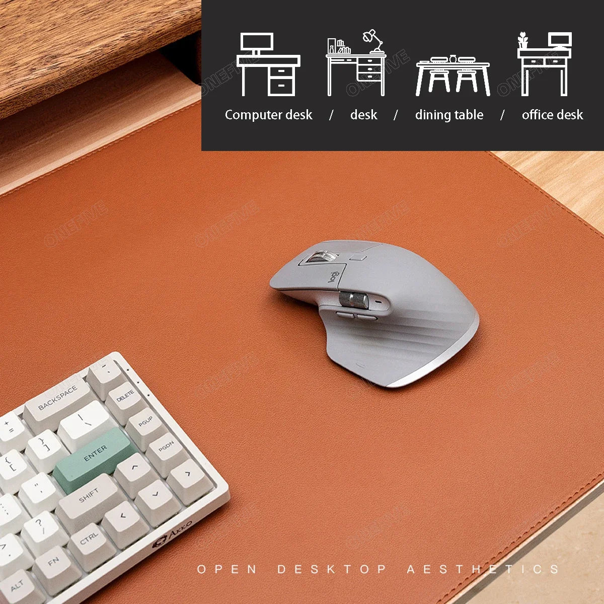 Graue ergonomische Computermaus auf einer braunen Leder-Unterlage neben einer weißen Tastatur.
