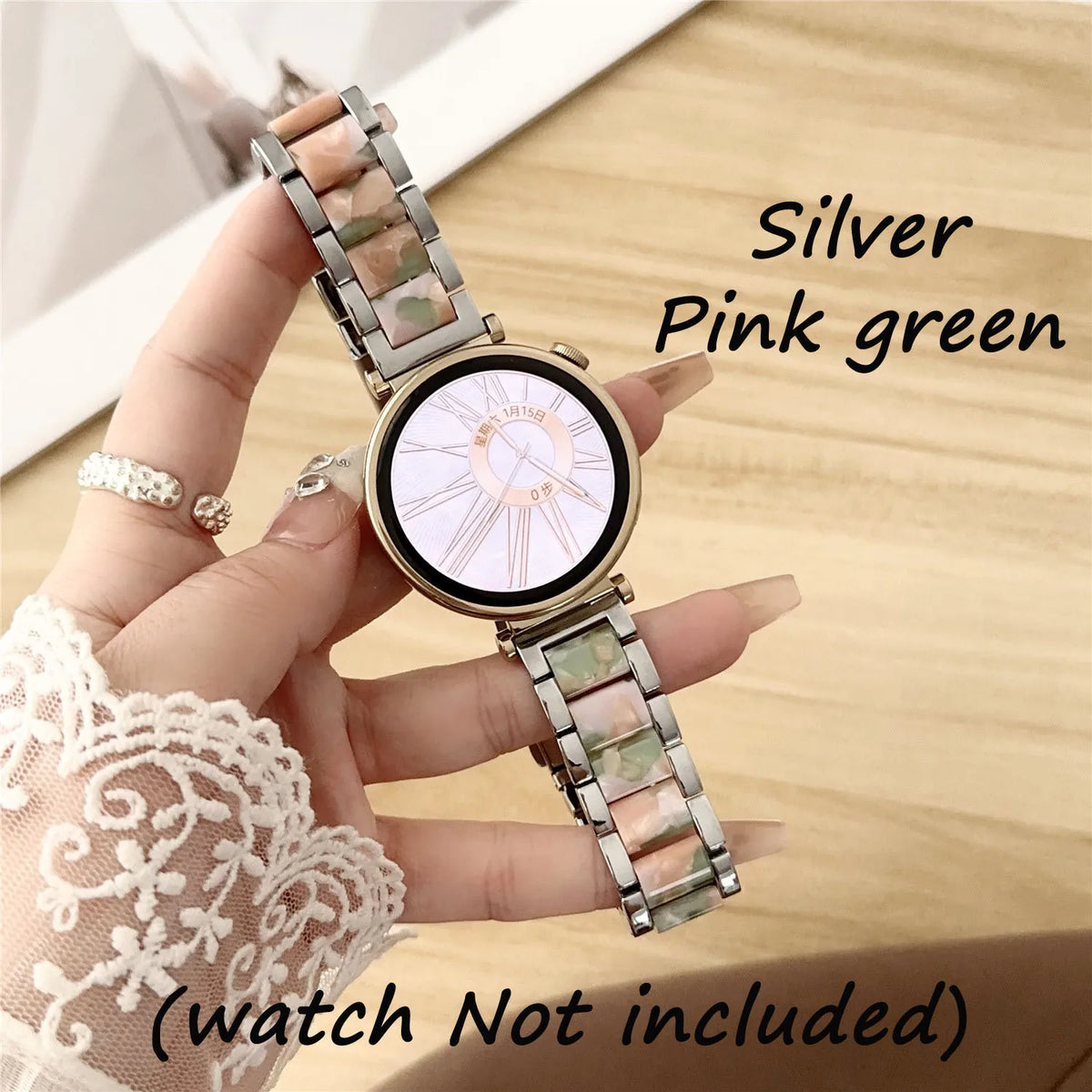 Eine Hand hält eine silber-rosa-grüne Harz-Metalluhr mit einem hellen Zifferblatt und passender Armband.