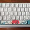 A white aluminum mechanical keyboard with light blue and red keycaps and a red flag design.