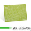 A green A4 cutting mat with grid guides and a dotted pattern on the bottom edge.