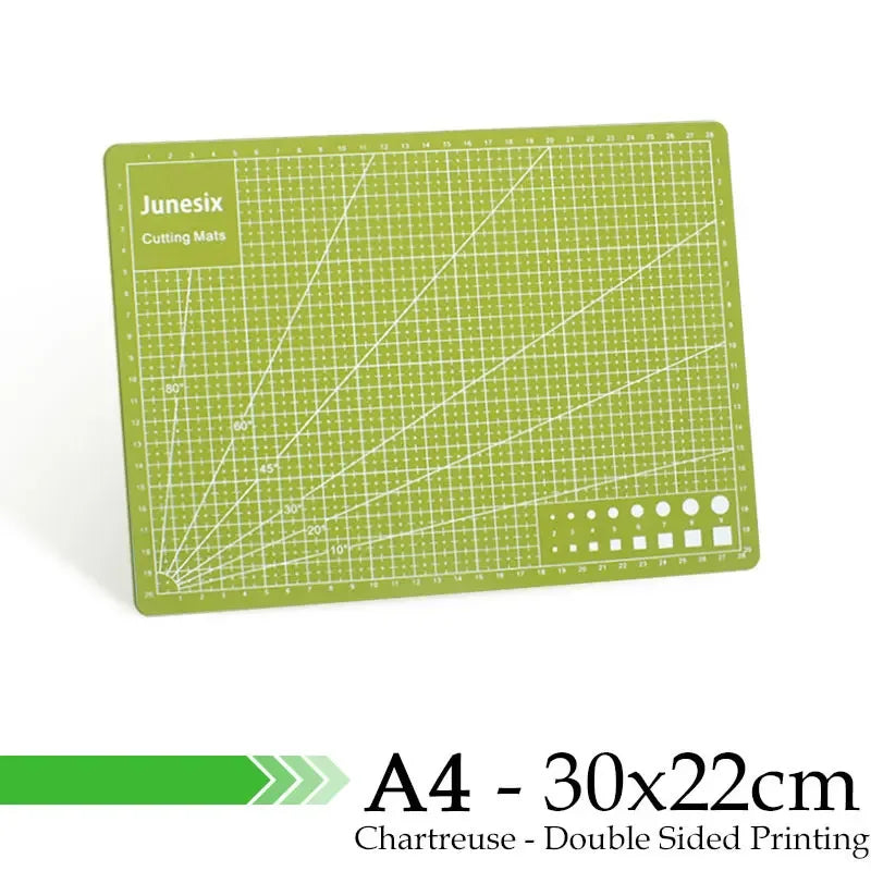 A green A4 cutting mat with grid guides and a dotted pattern on the bottom edge.