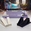 A purple ergonomic keyboard height adjuster stand with white keyboard components and a laptop displaying a vibrant scene.