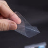 A hand is holding a clear protective sleeve designed for trading cards against a dark background.