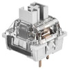 A close-up view of a gray wood mechanical keyboard switch housing with clear plastic components and metal pins.