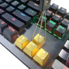 A close-up view of a mechanical keyboard keycap puller tool with gold-colored levers and plastic components.