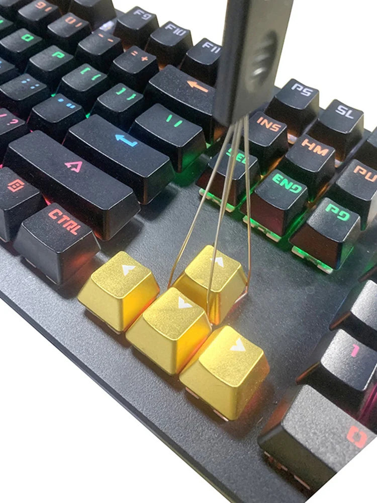 A close-up view of a mechanical keyboard keycap puller tool with gold-colored levers and plastic components.