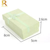 A rectangular light green jewelry gift box with a pale green ribbon tied on top.