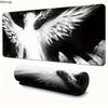 Black and white artistic image of a large angel wing on a desk mat or mouse pad