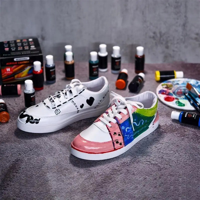 Ein Paar weiße und mehrfarbige Leinenschuhe neben verschiedenen Flaschen Acrylfarbpigmente.