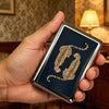 A hand holds a vintage stainless steel card and cash case featuring an embossed leopard print design.