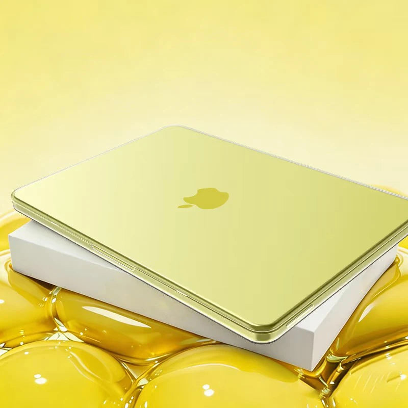 A gold Apple laptop is shown resting on a white protective case, surrounded by yellow liquid.