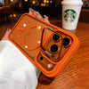 An orange MagSafe phone case with a built-in camera bracket and lens cover is held over a wooden table.