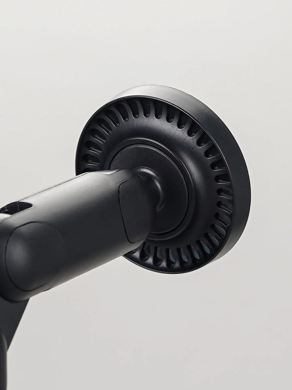 A close-up view of a black magnetic phone and tablet stand with a circular gripping mechanism.