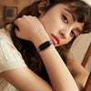 A close-up of a woman wearing a dark silicone replacement strap on her wrist.