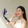 A woman holds an ultra-long selfie stick with a smartphone and Bluetooth remote in her hand.