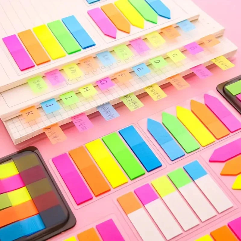 A collection of fluorescent PET sticky notes with index tabs arranged in rows on a white surface.