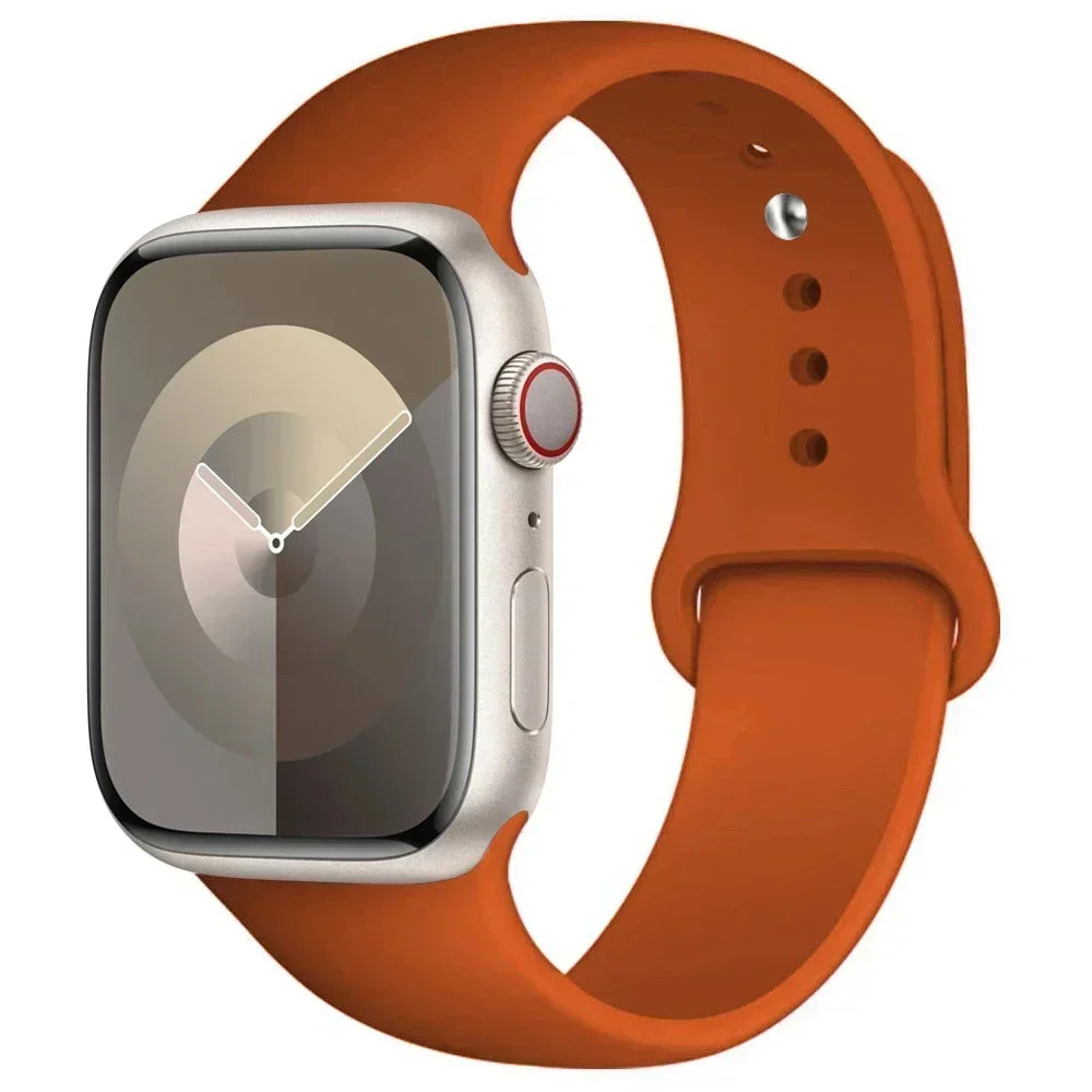 A silver Apple Watch is shown attached to an orange silicone sport band.