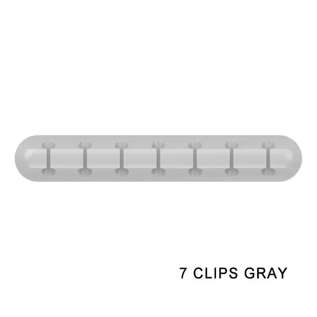 A translucent gray silicone cable organizer with seven clips.