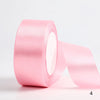 A roll of pink satin ribbon used for gift wrapping and DIY crafts.