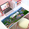 A large gaming mouse pad featuring Los Sims 4 scenery and characters placed on a white desk.