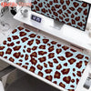 A large desk pad featuring a leopard print design with brown and tan spots on a light blue background.