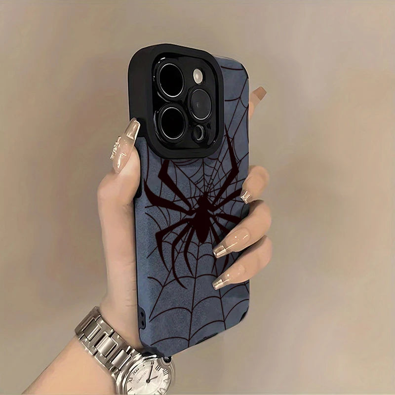 A hand holds a dark blue phone case featuring a black spider web design and a silver watch.