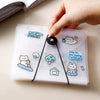 A hand is holding a clear plastic storage book filled with various stickers and documents.