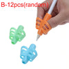 A hand holds an orange silicone pencil grip writing corrector, with a green and blue version visible below.
