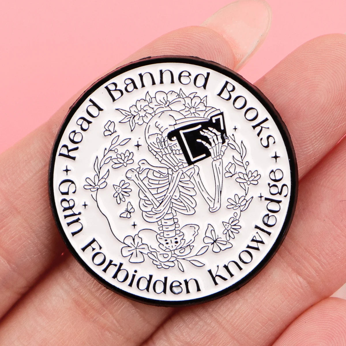 A black enamel lapel pin featuring a detailed illustration of a skeleton surrounded by books and text.