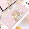 A pink cartoon gaming desk mat featuring a cute teddy bear and a fluffy white animal design.