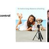 A man is using a detachable Bluetooth remote control and selfie stick tripod to take a photo.