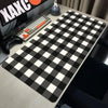 A black and white checkered desk mat is placed on a light-colored desk next to a keyboard.