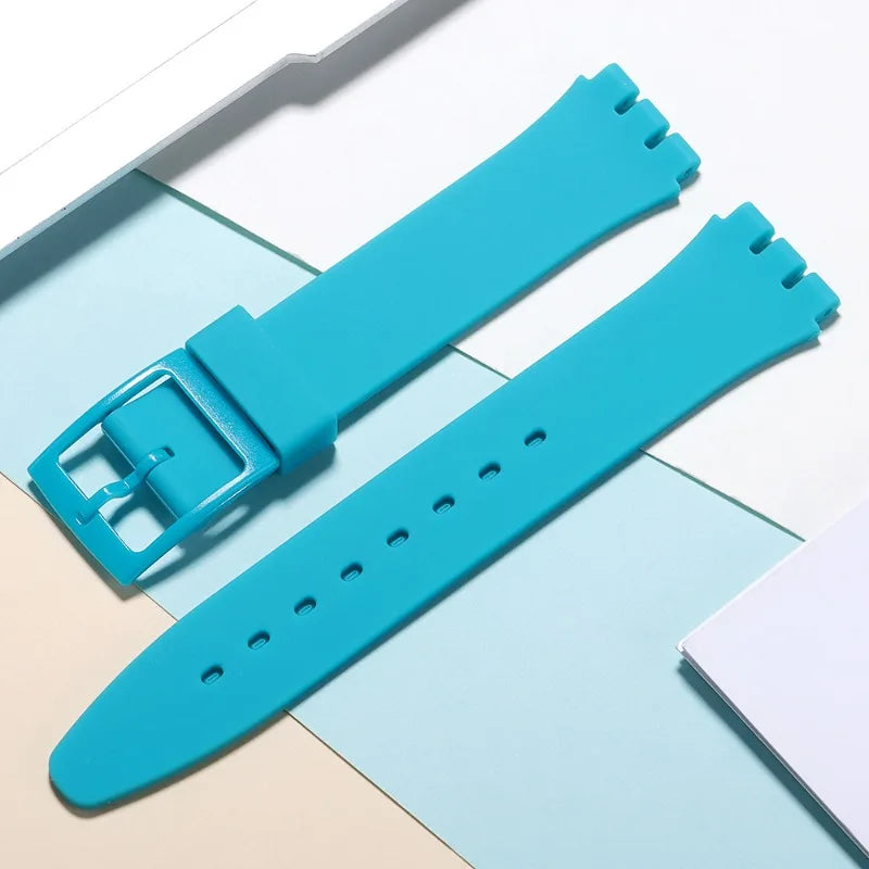 A teal silicone watch strap is shown next to its replacement tools on a light background.