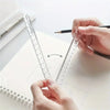 A hand holds a precision acrylic folding ruler set, measuring lines on a sheet of paper with a pencil.