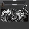 A large gaming mouse pad featuring a black and white liquid wave design, positioned under a computer monitor.