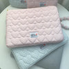 A stack of pink and light blue quilted laptop sleeves with a hello everything good luck tag.