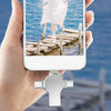 A hand holds a smartphone displaying a picture of a person walking on a wooden pier over blue water.