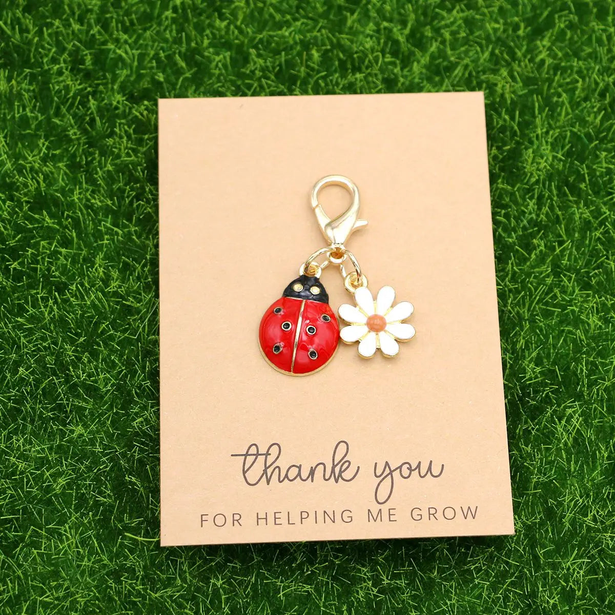 A small gold-colored keychain featuring a ladybug and a daisy on a kraft paper card.