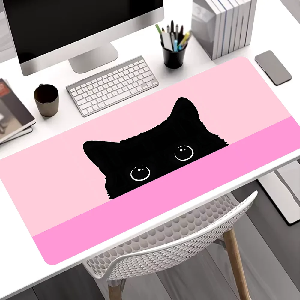 A black cat silhouette design on a pink mouse pad placed on a white desk.
