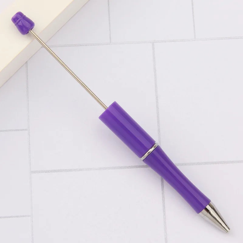 A purple DIY beadable pen with a silver tip resting on a white surface.