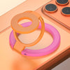 A pink and orange MagSafe double-sided phone ring holder stand resting on a light wooden surface.