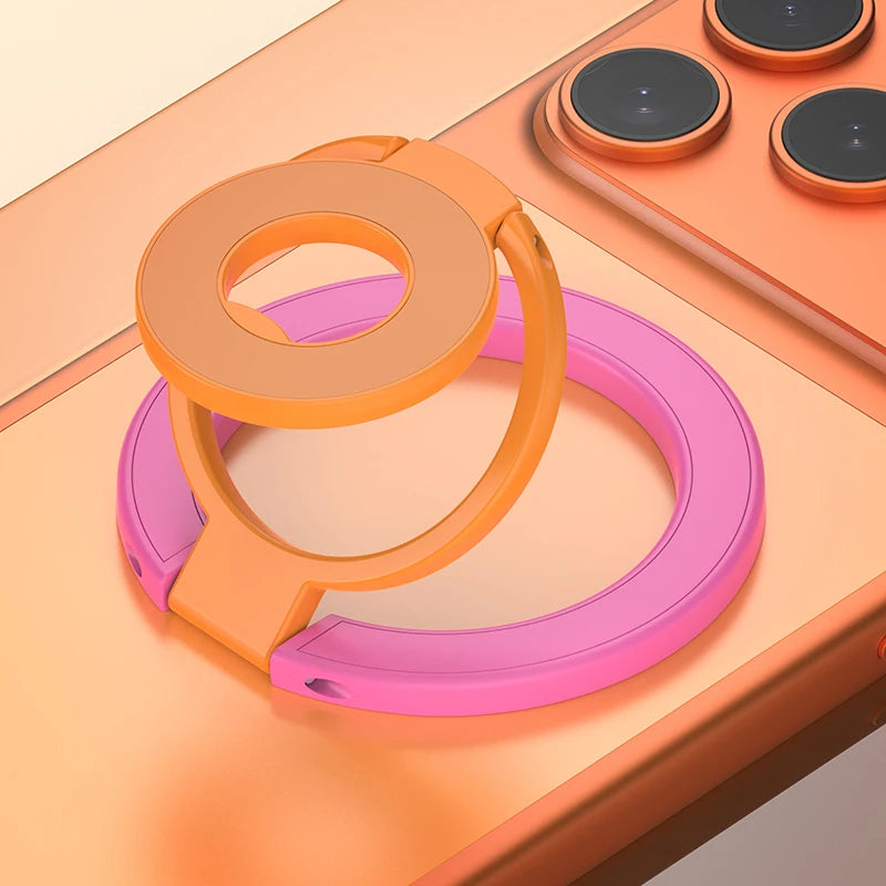 A pink and orange MagSafe double-sided phone ring holder stand resting on a light wooden surface.