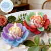 A set of five pastel colored ceramic flowers with lit candles arranged on a white table.
