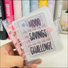 A clear binder with a pink cover and a purple sheet detailing a $1000 savings challenge.