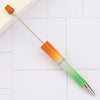 A DIY beadable pen set with orange and green colored barrels and a silver tip resting on a white surface.